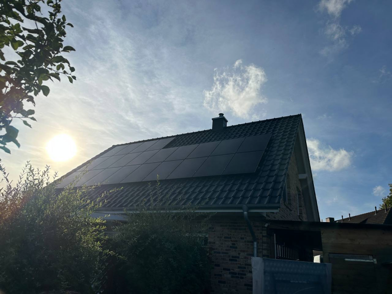 Haus mit Solarmodulen auf dem Dach, die Sonnenenergie vor einem sonnigen, bewölkten Himmel nutzen.