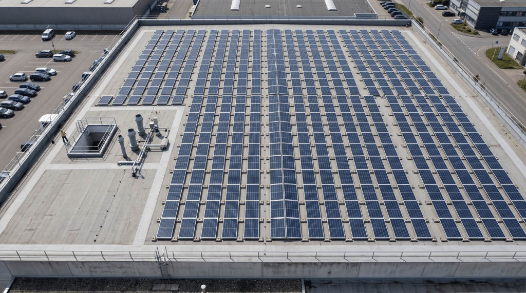 Flachdach mit aufgeständerten Solarmodulen in Ost-West-Ausrichtung, paarweise Rücken an Rücken montiert.