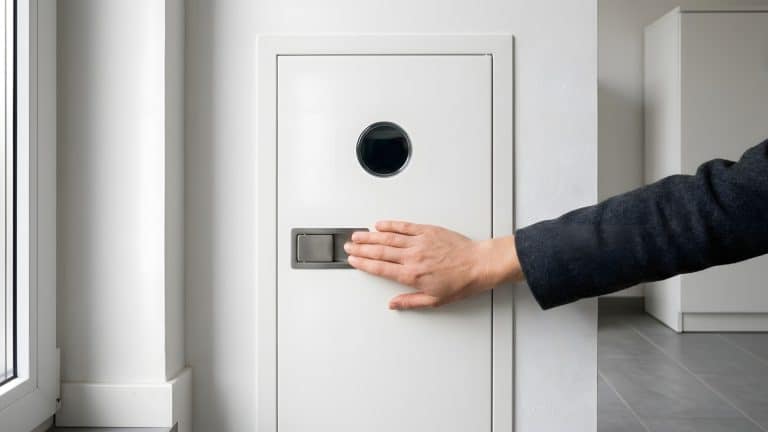 Hand am Griff eines geschlossenen weißen Zählerschranks im hellen Hauswirtschaftsraum