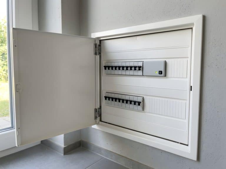 Geöffneter Zählerschrank mit einer kleinen grauen Steuerbox und grüner Kontrollleuchte
